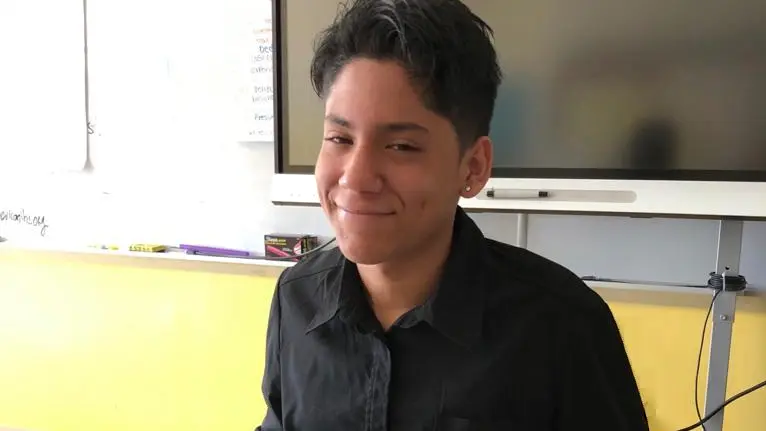 student wearing a black button up shirt smiling and looking at the camera